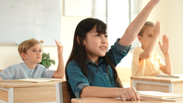 快乐的女孩在课堂上举手答问老师。教育学。图片下载