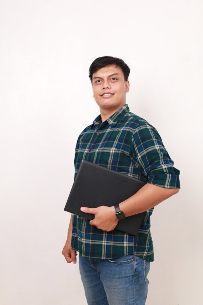 年轻帅气的亚洲大学生拿着笔记本电脑站着的照片图片下载