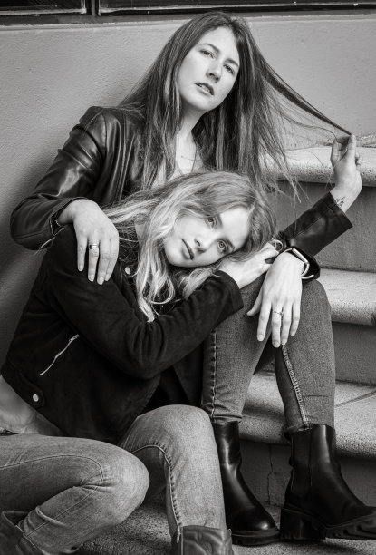 两个女性朋友在城市环境中坐在楼梯上的灰度照片图片下载