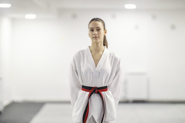 一个跆拳道运动员站在武术学校，看着镜头的肖像。图片下载