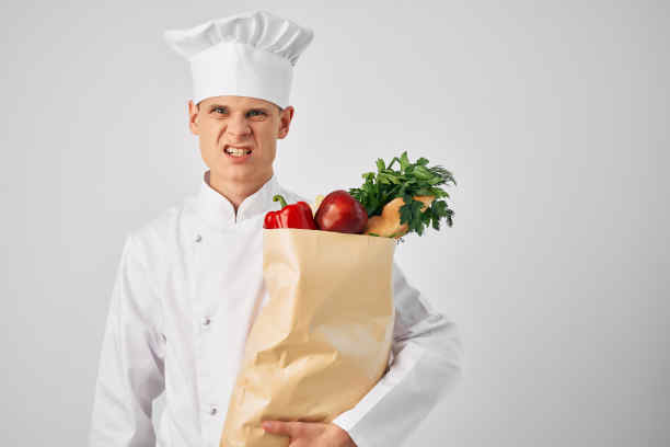 一个穿着厨师制服的男人，拿着一袋餐馆服务的食品杂货图片下载