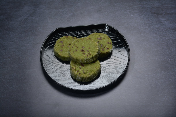 烘焙豪华抹茶绿茶与混合坚果巧克力片糖钻石貂皮圆饼干和黑盘金叉刀暗背景糕点甜点清真无麸质素食食品菜单图片下载