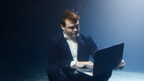 一个西装革履的商人正在水下摆弄笔记本电脑。图片下载