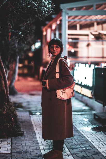 圣诞节走在街上的女人。背景中有夜晚城市灯光的散景图片下载