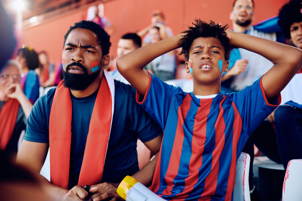 黑人孩子和他的父亲对他们的球队在体育场输掉一场比赛感到不满。图片下载