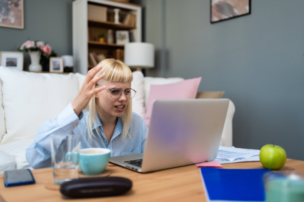 困惑的年轻女子在家里看着笔记本电脑，因为没有连接而感到困惑，在互联网上阅读在线新闻，烦恼的少女因电脑卡住问题，诈骗垃圾邮件，系统错误而生气图片下载