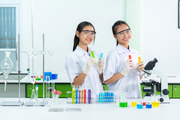 两名亚洲女科学家是实验室工作人员，她们拿着试管，用医用化学物质生产显微治疗提取物，她们有烧杯、量筒和实验设备。图片下载