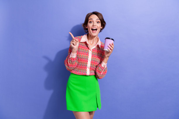 照片肖像的迷人的年轻女子咖啡纸杯点空空间穿时髦的印花衣服孤立在紫罗兰色的背景图片下载