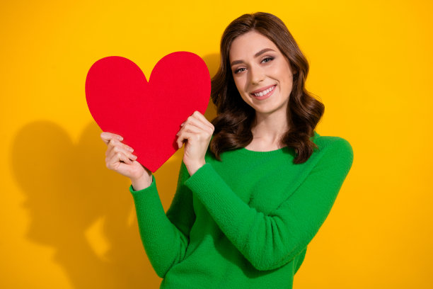 照片中开朗温柔的女人穿着时髦的衣服展示红牌庆祝母亲节孤立在黄色背景图片下载