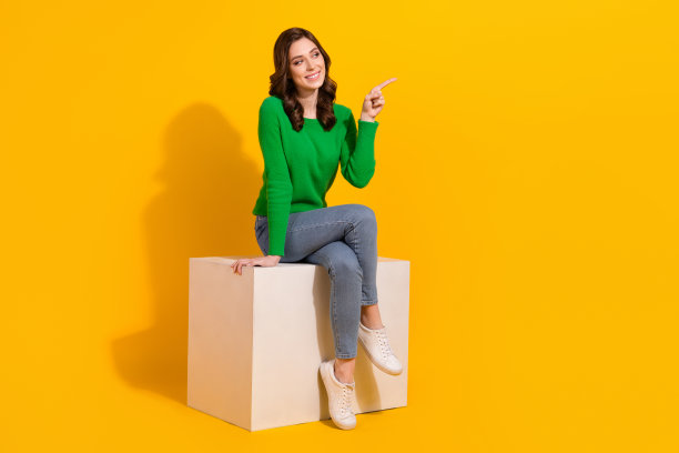 女性全身照片独自坐白色讲台直接手指空白空间广告牌黑色星期五隔离在黄色背景图片下载