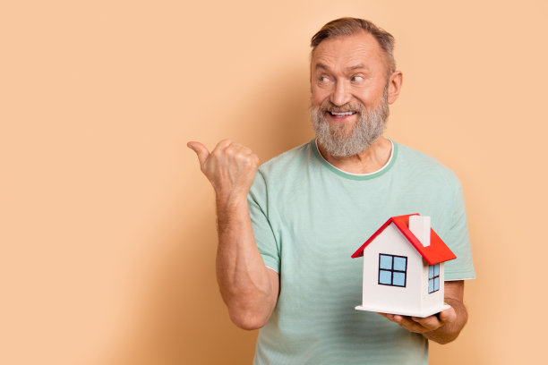 照片正面的好男人穿着时髦的衣服呈现房地产机构的空白空间孤立的米色背景图片下载