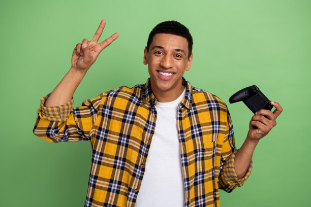 年轻人的照片广告游戏俱乐部的空闲时间周末度过空闲时间显示v标志持有手柄孤立的绿色背景图片下载