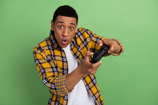 近距离照片的年轻人噘起嘴唇，黄色衬衫，使用无线游戏手柄视频游戏孤立的绿色背景图片下载