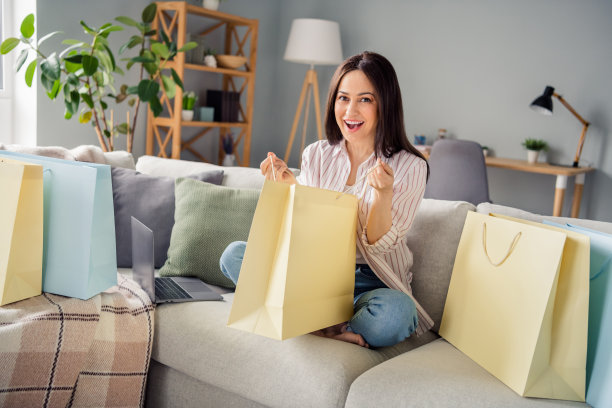全尺寸照片正面印象深刻的女孩坐在沙发上持有打开网上商店送货包裹现代室内室内图片下载