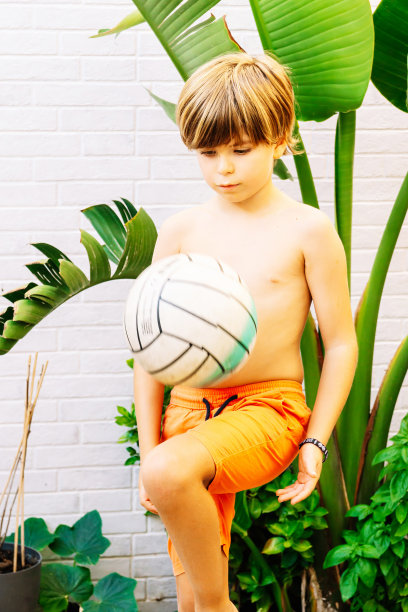 一个9岁的白人男孩在花园里玩足球的照片。概念春夏活动。图片下载