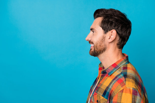 照片中英俊的年轻男性的肖像看起来空的空间侧面横幅穿着时尚的格子装孤立在蓝色的背景图片下载