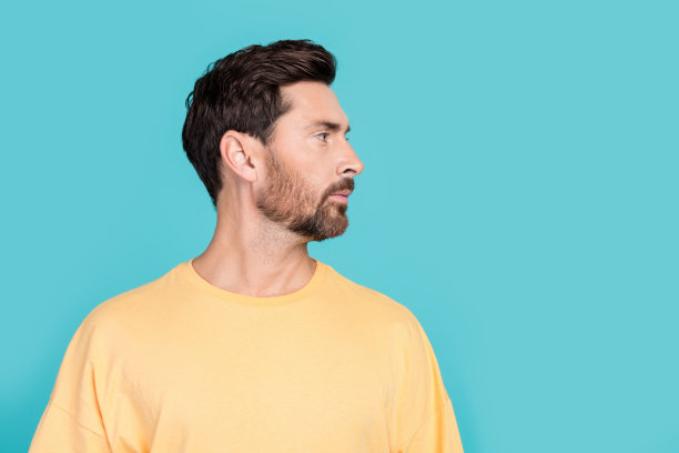 个人资料照片，严肃自信的男人穿着黄色时髦的t恤，看起来发型类型的选择孤立的海蓝宝石色背景图片下载