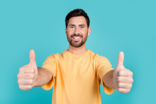 近距离照片的年轻帅哥穿着黄色t恤，显示双像标志黄金率孤立在蓝色背景图片下载