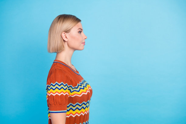 漂亮女孩的侧面照片，短发，穿着针织t恤，看着美容院，蓝色背景上的空白空间图片下载