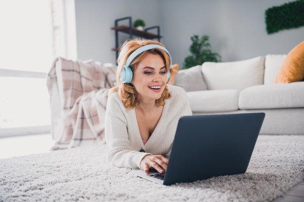 迷人的开朗的女士的照片铺设地毯地板听音乐耳机使用无线笔记本电脑现代室内平面室内图片下载
