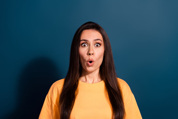 照片中，无言以对的女人留着长发，穿着黄色的t恤，在深蓝色的背景上给人留下了深刻的印象图片下载