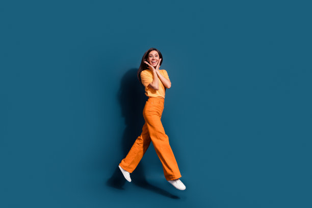 活跃的拉丁模特的全身长度的照片跳跃触摸脸颊惊讶于精品价格孤立的深蓝色背景图片下载