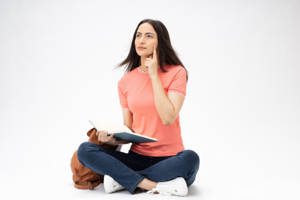 全身尺寸的年轻女孩读书坐在地板上穿着牛仔裤牛仔粉t恤鞋孤立在白色背景股票照片图片下载