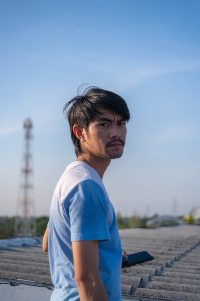 一个黑脸的年轻人站在屋顶上，背景是蓝色的。图片下载