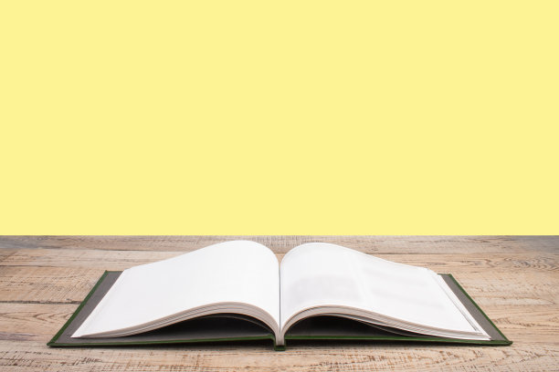 打开书。组成与精装书，扇页在木制甲板桌和黄色背景。书堆积。回到学校。副本的空间。教育背景。图片下载