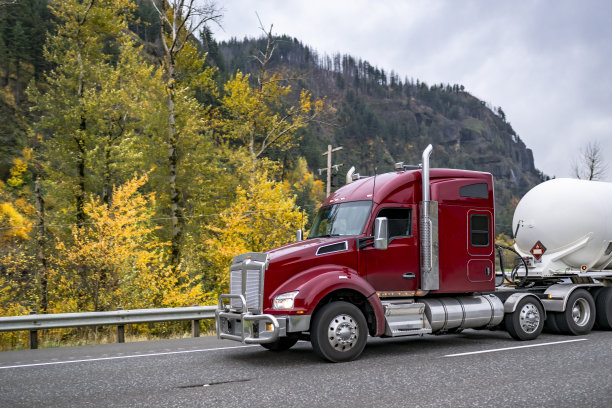 加长驾驶室酒红色长拖车大钻机半卡车与格栅保护运输易燃化学品在重型坦克半挂车运行在秋季公路上图片下载