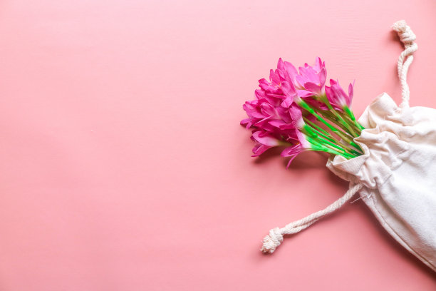 俯视图照片的花束粉红色的百合在一个串袋孤立的粉红色背景与copyspace。春花在粉红色的平地上躺着。贺卡，节日概念。西风花图片下载