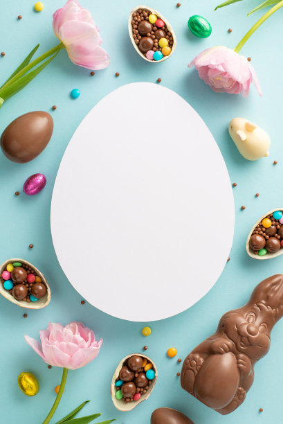 时尚的复活节糖果系列。俯视图的垂直照片显示，在淡蓝色的背景上，巧克力蛋被打破了，里面有彩色的糖果、糖果和郁金香，还有一个鸡蛋形状的空间用来放笔记图片下载