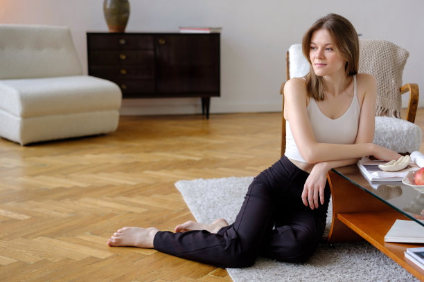 美丽的年轻女孩赤脚坐在温暖柔软的地毯上，倚在咖啡桌上，在舒适的房间里放松图片下载