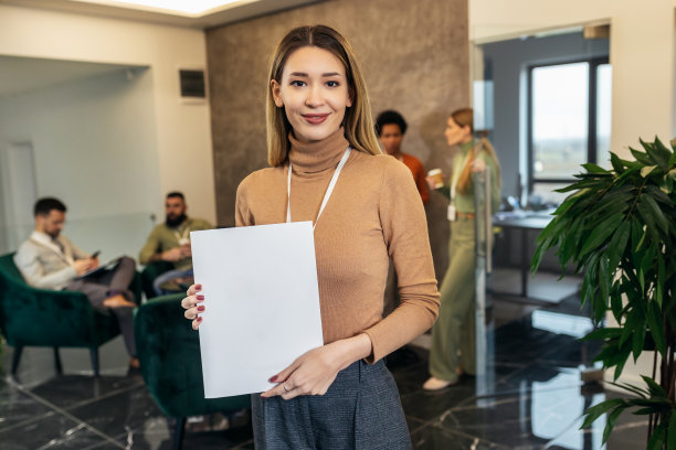 一位穿着随意的女商人站在办公楼的大厅里，面对着一个商业团队图片下载