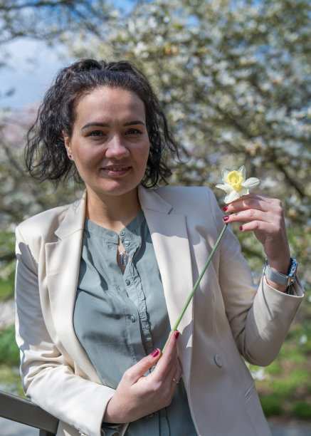 一个可爱女人的特写肖像。模特手里拿着一朵水仙花，温柔地看着那朵花图片下载