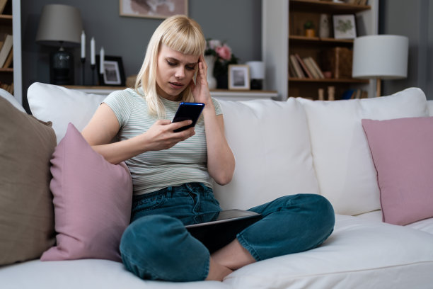快乐的千禧一代金发少女查看社交媒体在家里拿着智能手机微笑的年轻女子使用手机应用玩游戏网上购物订购送货放松在沙发上网上约会图片下载