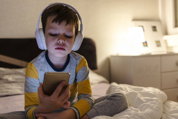 晚上，男孩的脸，耳机和平板电脑在家里阅读电子书，看动画片和玩电子学习应用程序上的视频游戏。孩子，孩子和听多媒体，音乐和流媒体电影的数字技术。图片下载