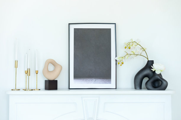 时尚的房间装饰着兰花花瓶，复古的金属烛台和蜡烛，壁炉架上的图片。白色现代装饰壁炉架在室内设计斯堪的纳维亚客厅。图片下载