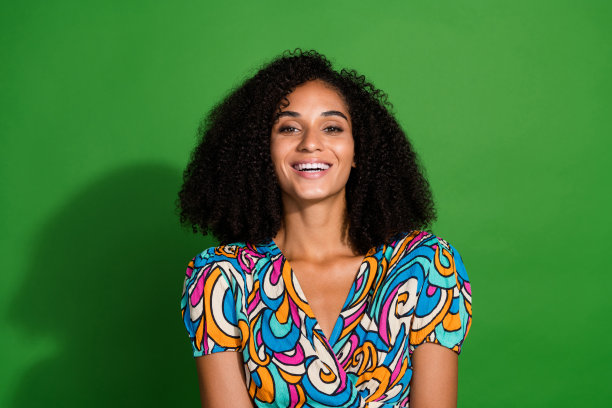 照片中乐观快乐可爱的女孩穿着夏天鲜艳的印花衣服，孤立在绿色的背景上图片下载