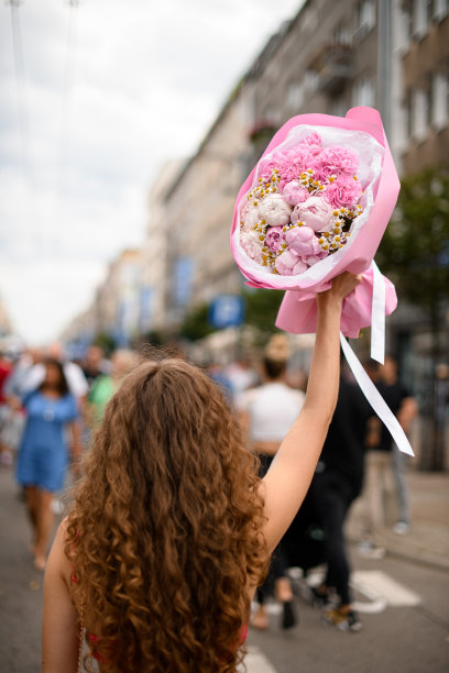 城市街道上，卷发女孩手捧一束温柔的鲜花图片下载