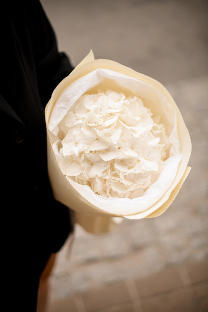 一个女孩站在城市街道上，手里拿着一束别致的白花图片下载