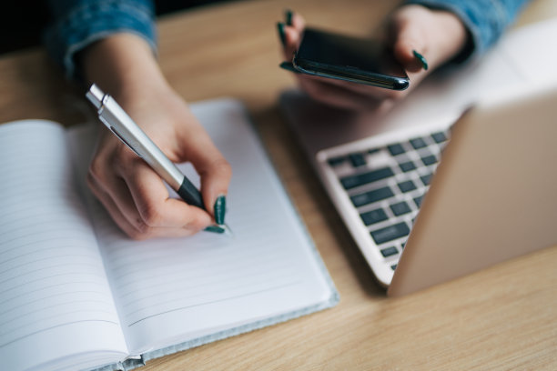 自由职业女孩在咖啡馆用笔记本电脑和手机写字的特写照片图片下载