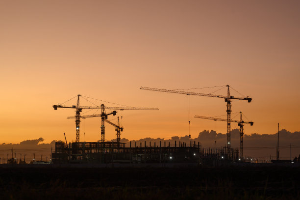 夕阳下的橘黄色夜空下的建筑剪影。图片下载