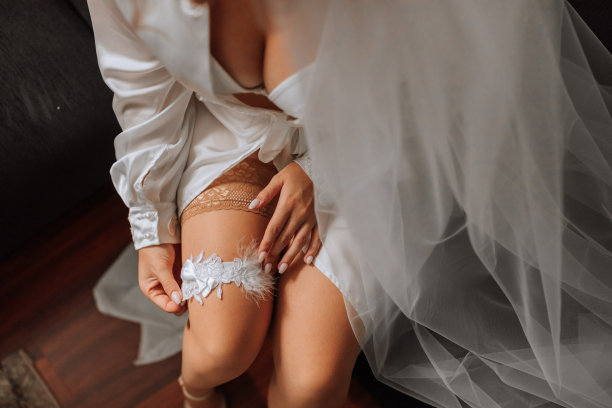 做着法式美甲的新娘手里拿着一条白色吊袜带。特写照片。新娘穿上结婚吊袜带，准备举行婚礼图片下载