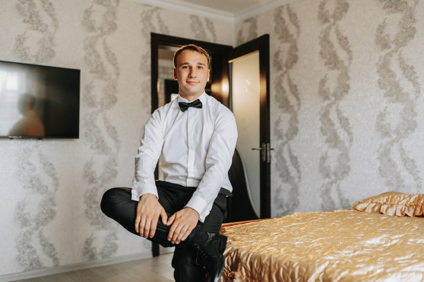 准备迎接新郎新娘的早晨。一个优雅的男人为婚礼庆典穿衣服的人像照片。新郎穿着白衬衫，打着领结图片下载