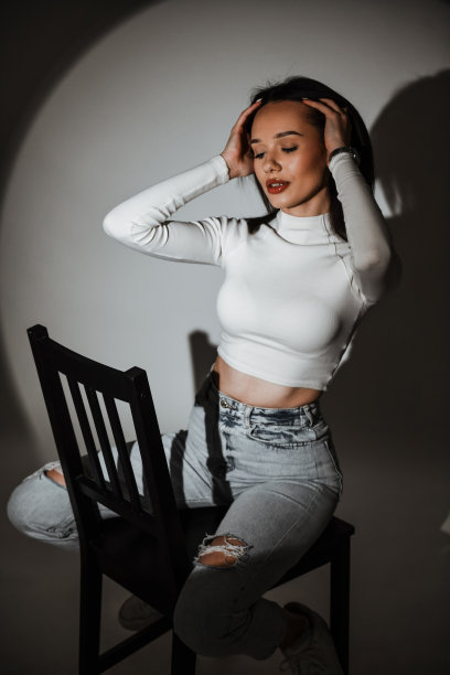 美丽的女性把手放在头发上，在阴影中放松地坐在椅子上图片下载