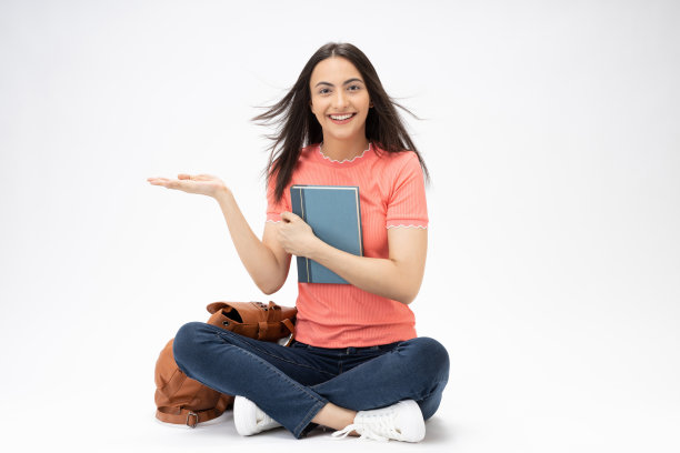 全身尺寸的年轻女孩读书坐在地板上穿着牛仔裤牛仔粉t恤鞋孤立在白色背景股票照片图片下载