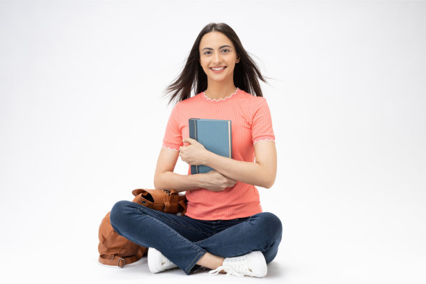 全身尺寸的年轻女孩读书坐在地板上穿着牛仔裤牛仔粉t恤鞋孤立在白色背景股票照片图片下载