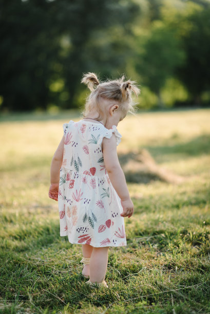 日落时分，孩子在田野里玩耍。美丽的女孩在大自然中漫步。特写镜头。一个可爱的孩子在公园的夏季肖像。女儿站在有散景的春天花园的户外。图片下载