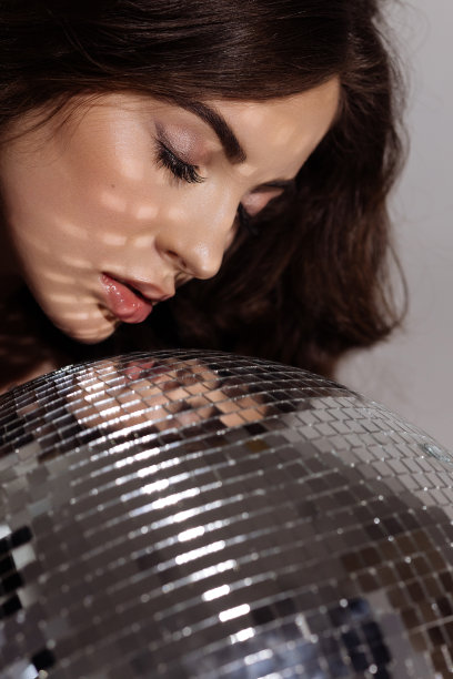 黑发女子手持迪斯科球展示时尚与美丽图片下载